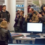 Press cameras surround a contributor describing her collection to a volunteer